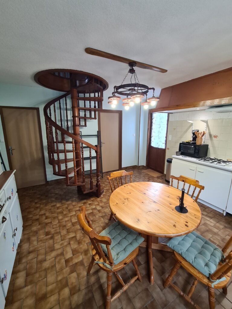 Pièce de vie avec cuisine équipée et escalier en colimaçon